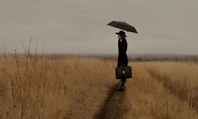 You Are Being Affected by the Trauma of Your Ancestors! image of a woman on a trail in an open field and holding a suitcase