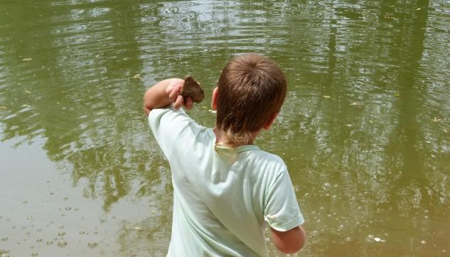 A photo of a young boy throwing stones into a lake.&nbsp;Image by Marc Pascual from Pixabay.&nbsp;