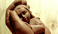 a clay sculpture of a child being held in a supportive hand