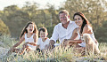 a joyful family sitting together outside in an meadow
